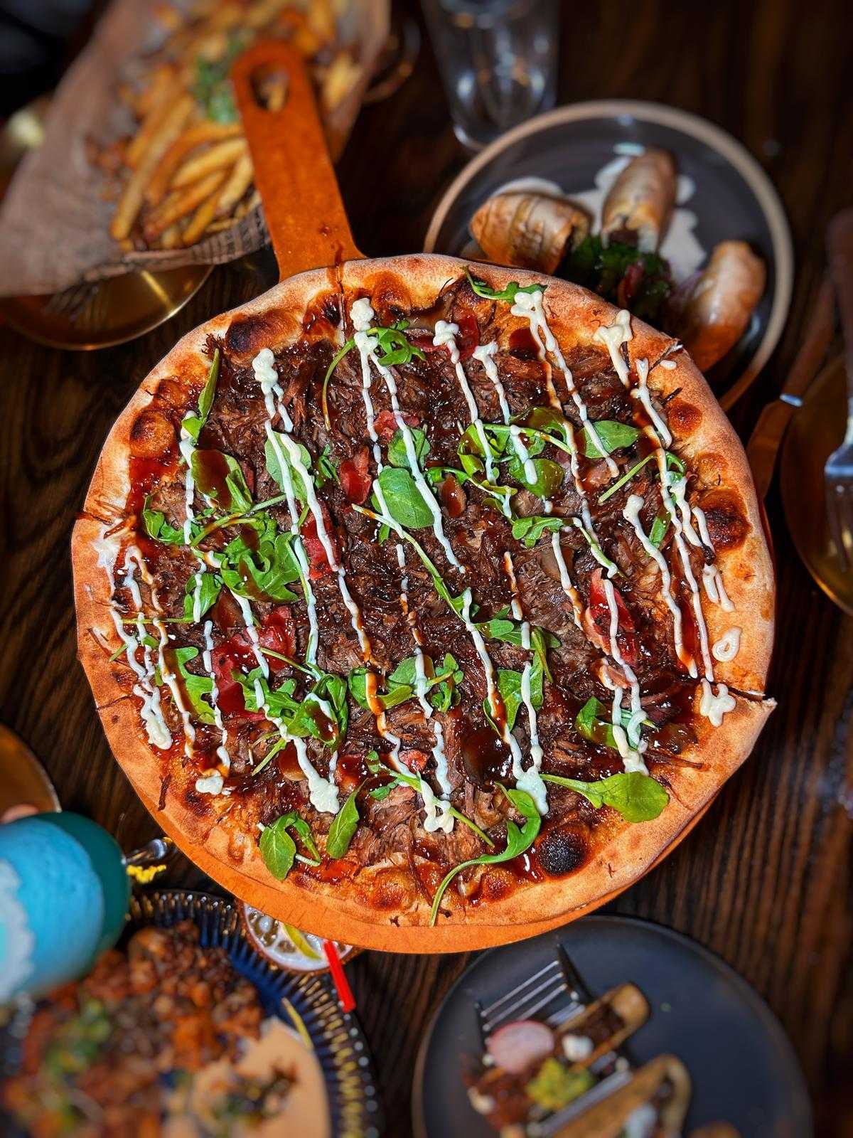 Meat pizza with arugula and garlic aioli on the table