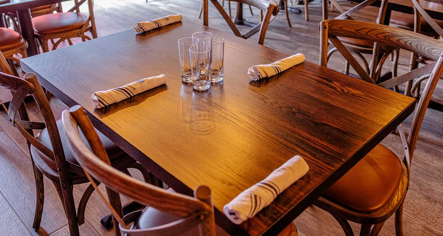 Set table with rolled napkins and cross-back chairs