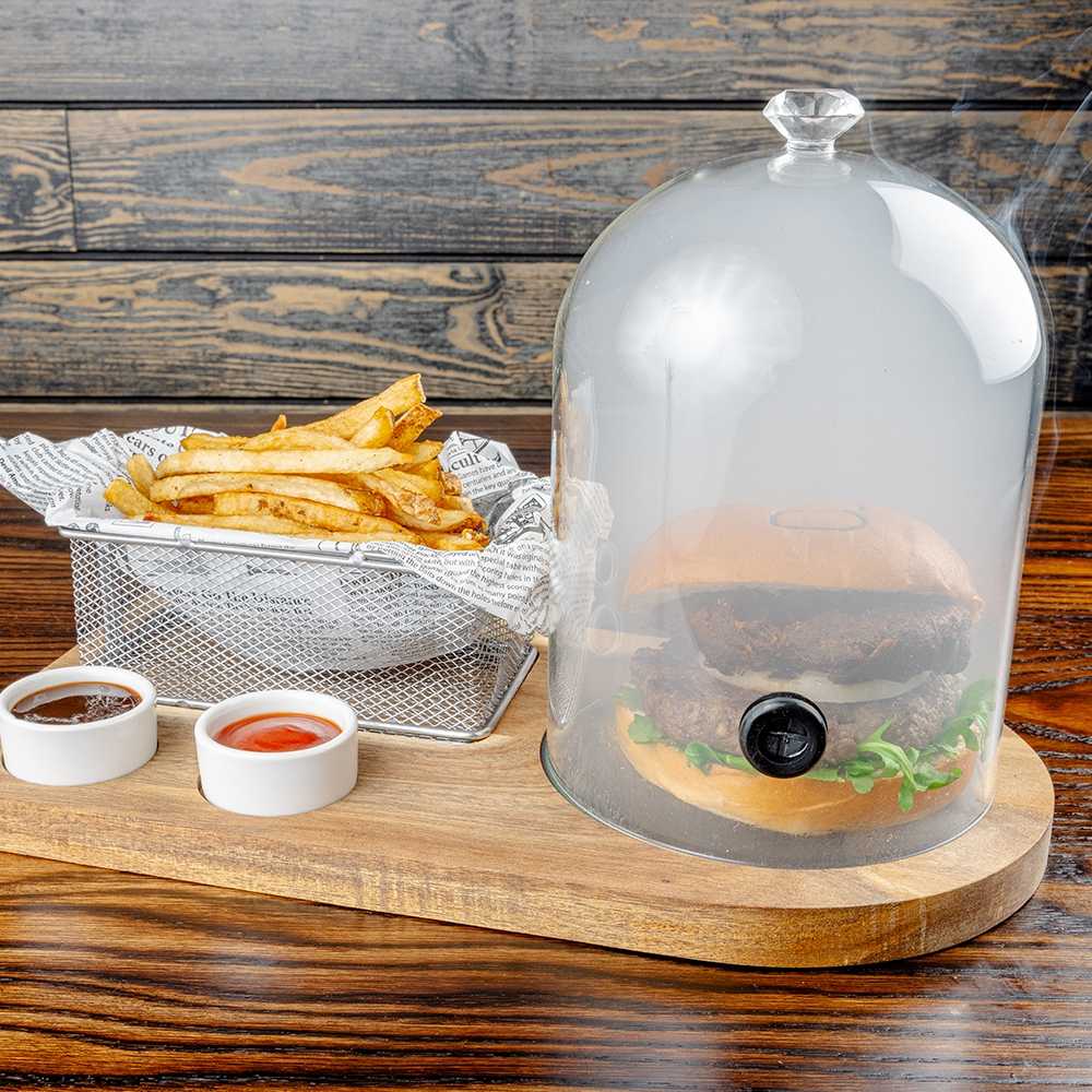 Burger under a smoke-filled glass cloche with fries